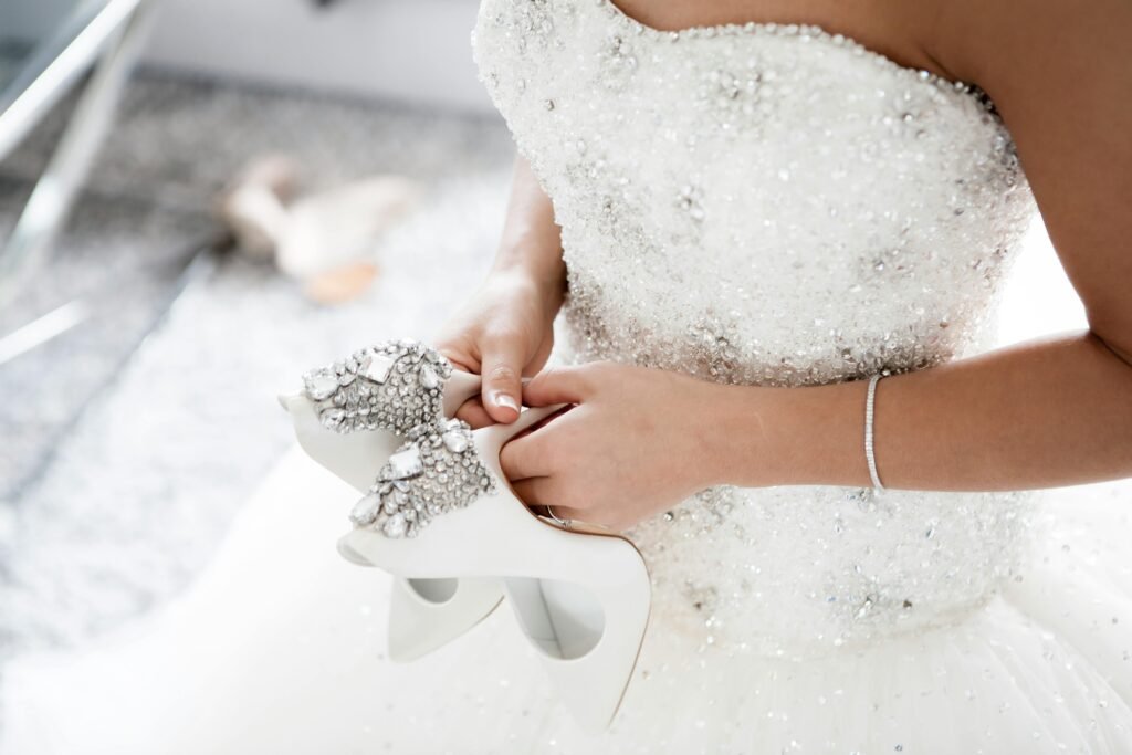 Bridal Gown Alterations – Eva’s Alterations Jacksonville Bride in crystal-embellished wedding gown holding jeweled heels – Eva’s Alterations Jacksonville